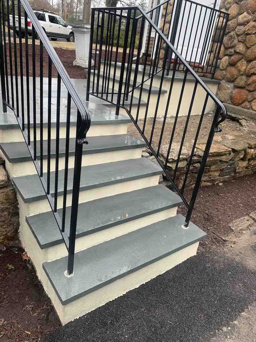 Stone steps with black handrails outdoors.