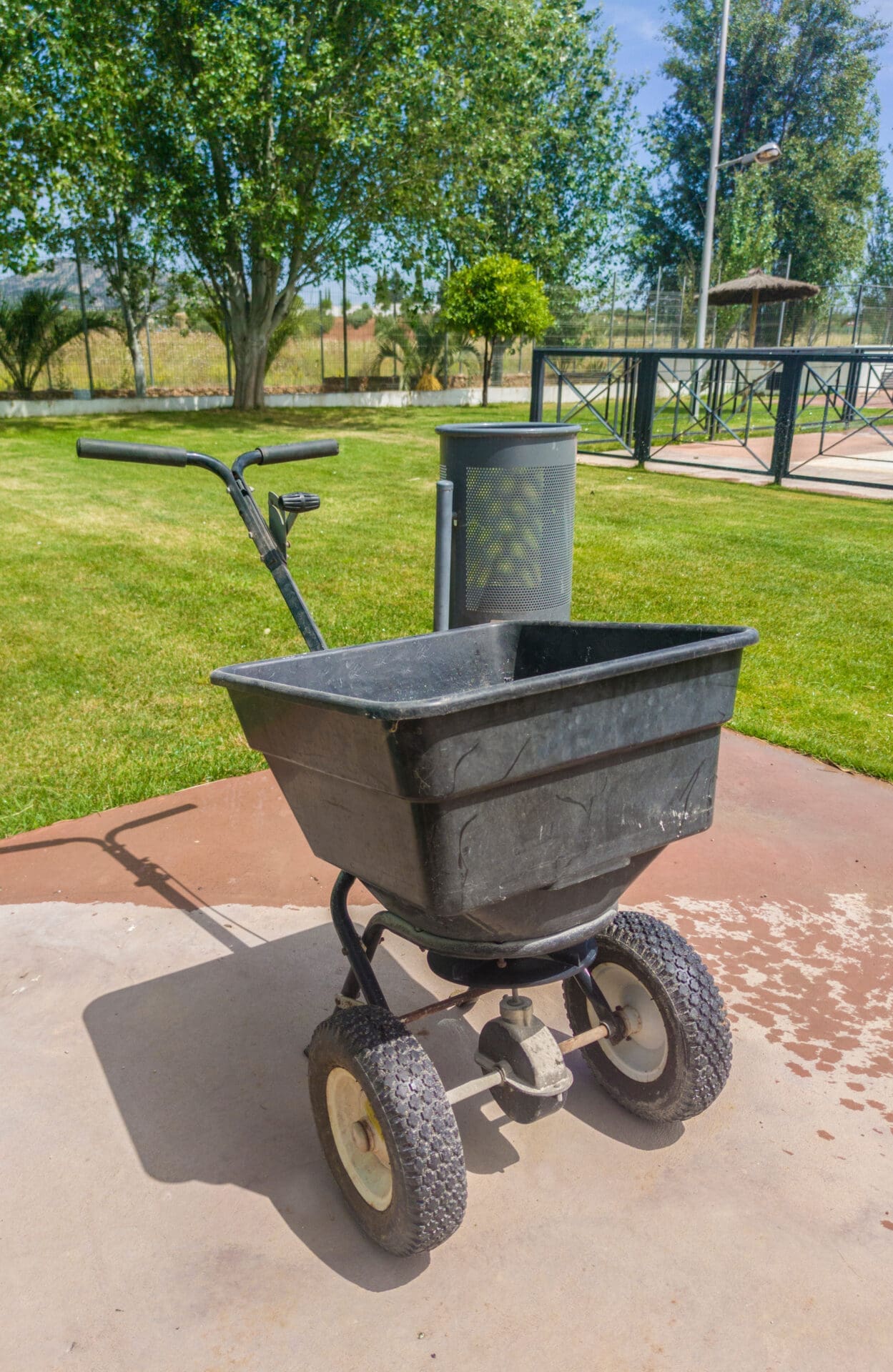 Garden spreader on lawn with trees and fence.