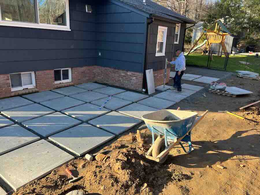 Backyard patio construction with cement slabs and wheelbarrow.