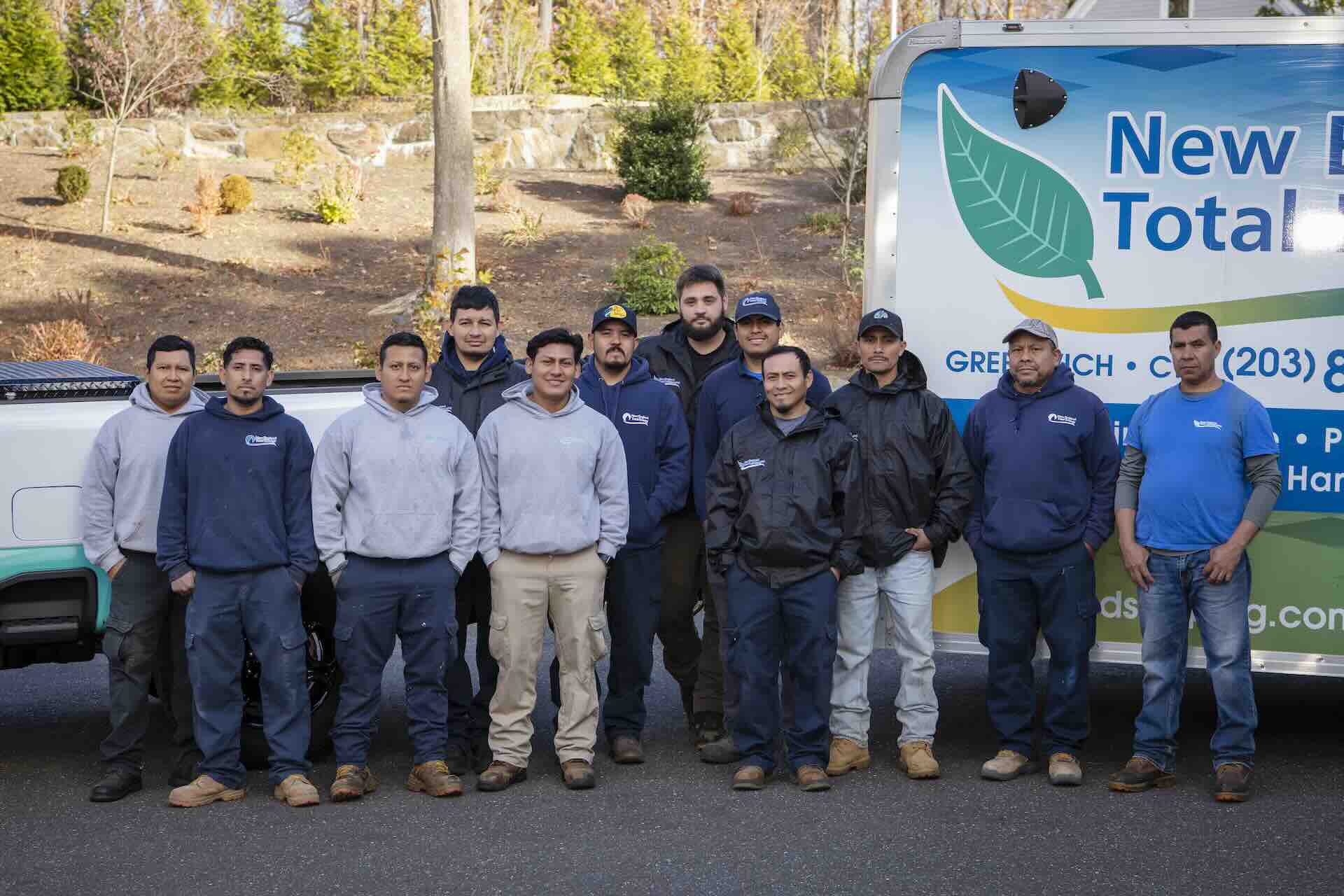 Crew members of New England Total Landscaping posing next to their truck and trailer.